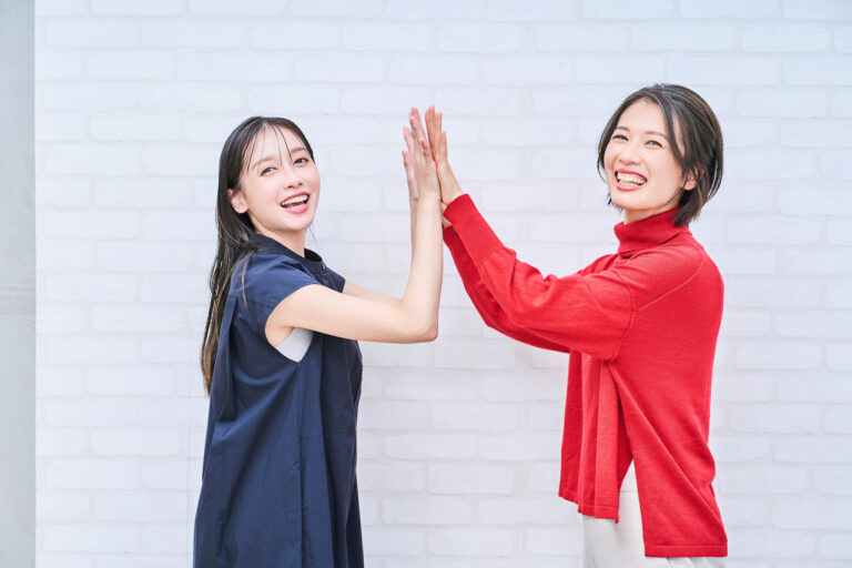 Women smiling and high-fiving indoors